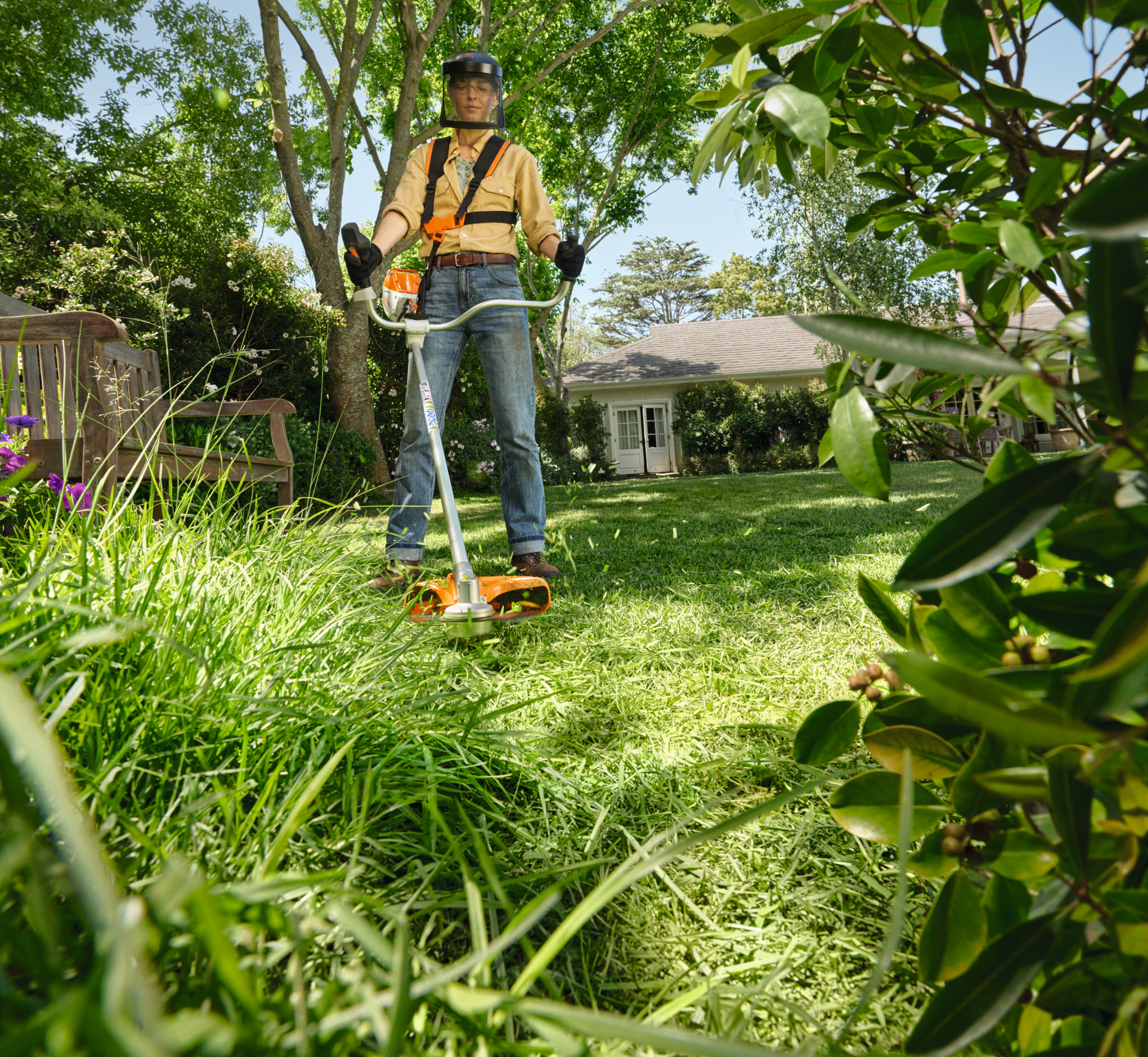 En person trimmar gräs med en batteritrimmer
