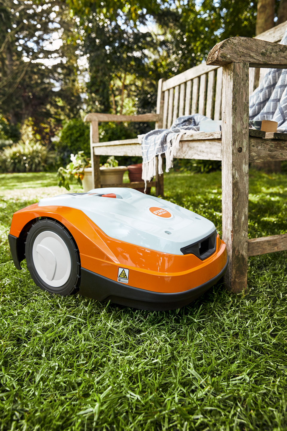 Robotgräsklippare STIHL iMOW® RM 522 på en grön gräsmatta intill en bänk