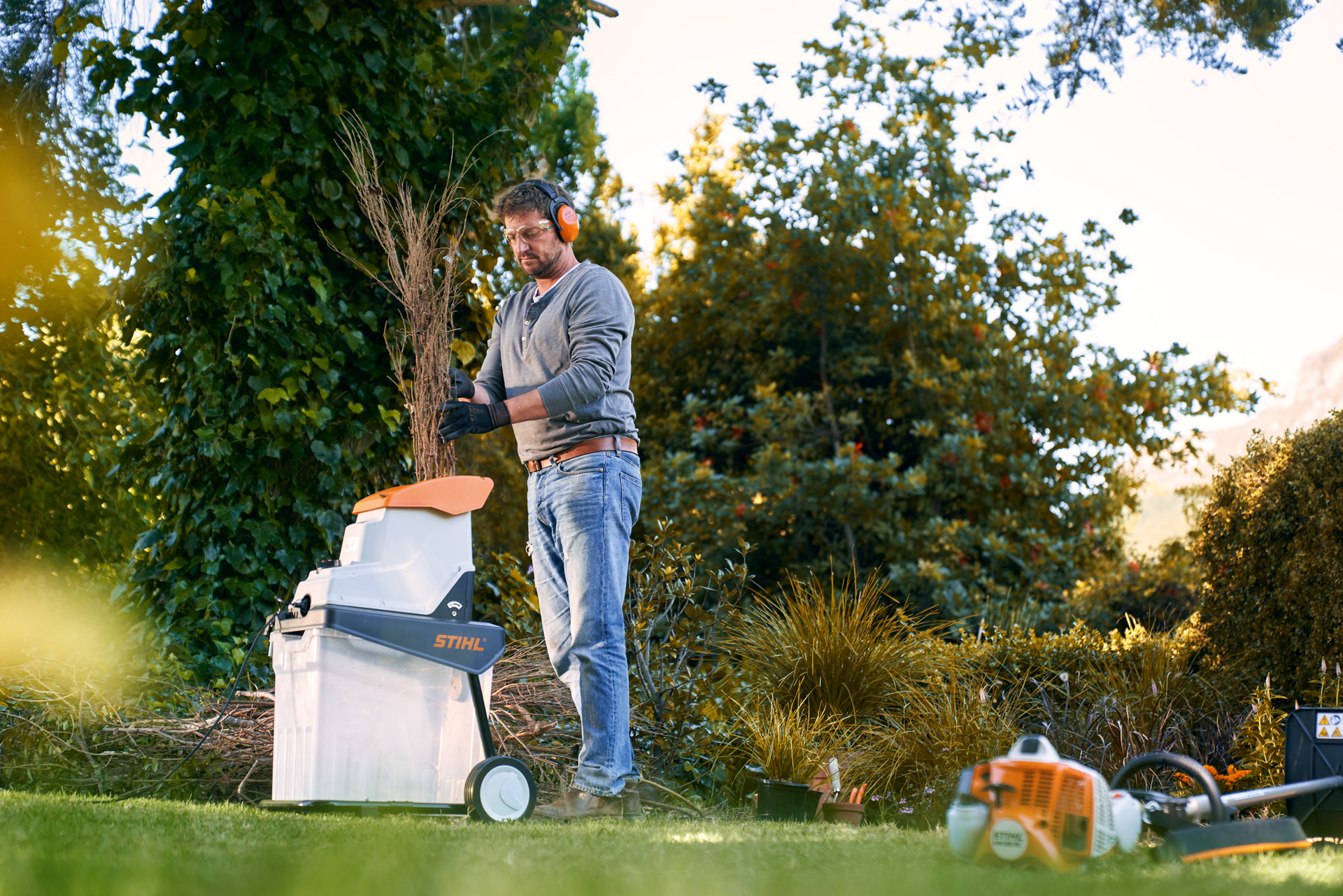 En man med hörselskydd kapar grenar före kompostering med en STIHL eldriven kompostkvarn GHE 140